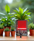 LED Chaser Soldering Practice Kit With 81 LEDs On A Handy PCB Board For STEM Electronics Projects And School Learning Diy EK1974, lit in red, surrounded by potted plants.