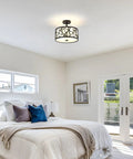 Modern bedroom with low-profile ceiling light, cozy white bedding, blue accent cushions, and bright natural light from patio doors.