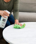 Person using All Purpose Cleaner Spray For Home And Kitchen Multipurpose Multisurface Cleaner For Glass Countertops Appliances Upholstery And More Unscented 32oz Pack Of 2 on a marble table with a green cloth