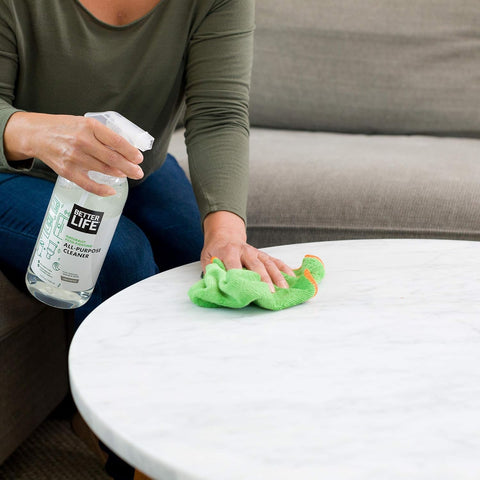 Person using All Purpose Cleaner Spray For Home And Kitchen Multipurpose Multisurface Cleaner For Glass Countertops Appliances Upholstery And More Unscented 32oz Pack Of 2 on a marble table with a green cloth