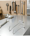 Heavy Duty T Handle Manhole Cover Hooks For Sewer And Septic Tanks Hella Tough Metal Lifters on a workbench, tools in background.
