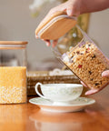 Airtight Glass Storage Jars Set Of 6 37 Oz Each With Bamboo Lids For Tea Coffee Flour Sugar Snacks Spices Candy And Cookies, one jar being opened.
