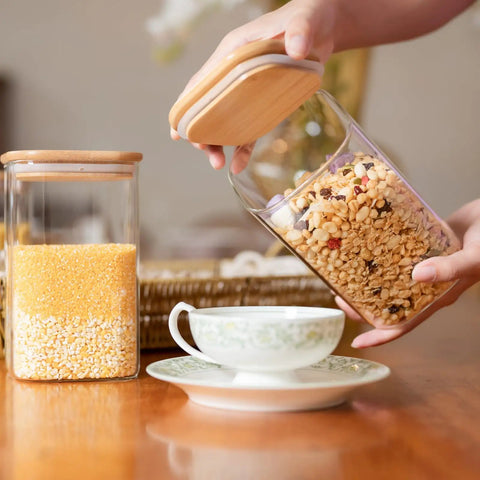 Airtight Glass Storage Jars Set Of 6 37 Oz Each With Bamboo Lids For Tea Coffee Flour Sugar Snacks Spices Candy And Cookies, one jar being opened.