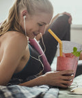 Woman using 2 Pack 24 Oz Blender Cups With Lids And Cup Brush For Auto IQ Blenders, enjoying smoothie on sofa, BPA-free