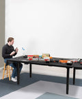 Person assembling model train set on Heavy Duty VIVO 4 Leg Black Electric Dual Motor Standing Desk Frame For 60-130 Inch Tops.