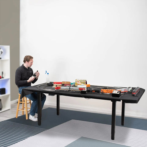 Person assembling model train set on Heavy Duty VIVO 4 Leg Black Electric Dual Motor Standing Desk Frame For 60-130 Inch Tops.