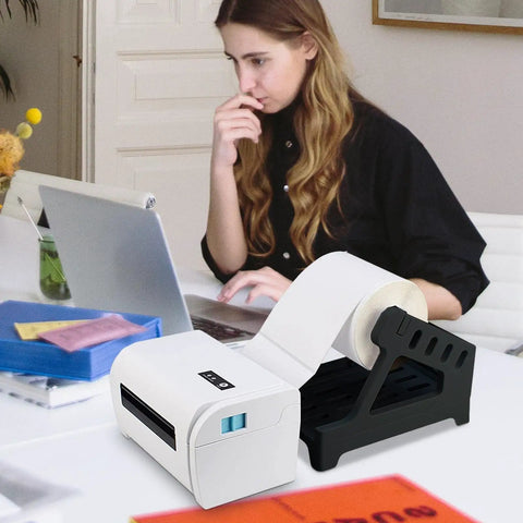 Real Deal Label Roll Organizer Desk Stand For Thermal Printers And Fan Fold Stickers Rack near a laptop in an office setup.