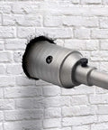 2-1/2 inch concrete hole saw with 65mm wall drill bit on a metal shank, installed in white brick wall
