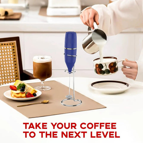 Handheld Milk Frother 14,000 RPM Drink Mixer Wand With Stand next to coffee cup and dessert on table.