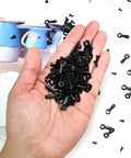 Close-up of a hand holding black metal turn-button fasteners with screws for picture frames (100 pcs)