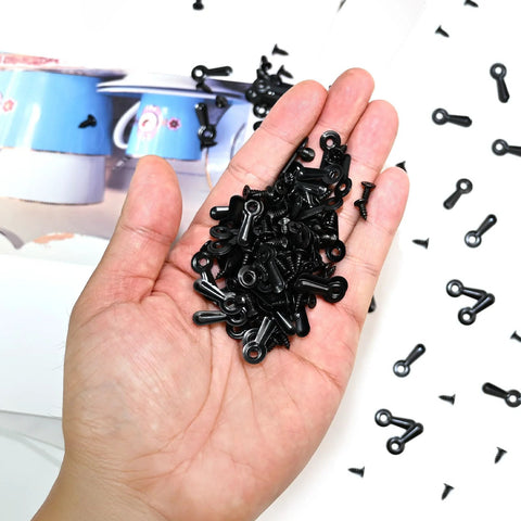 Close-up of a hand holding black metal turn-button fasteners with screws for picture frames (100 pcs)