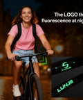 Woman riding bike with Dope Mountain Bike Handlebar 31.8mm Clamp, glow in the dark logo, viewed at night.