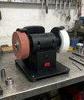 Heavy Duty Bench Grinder With Debris Guard And Anti Slip Base For 18V Lithium Batteries on a workshop table, compact and stable design.