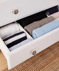 Open drawer with folded clothes, featuring Four Pack Racing Style Round Cabinet Knobs One And A Quarter Inch Diameter Zinc Alloy Drawer Pulls
