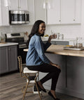 Woman sitting on Stylaire Retro Chair And Step Stool With Flip Up Seat Black Vinyl Upholstery Chrome Steel Frame