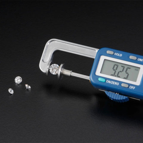 Digital Gauge Mrg-25 Electronic Pearl Calipers for Diamond Gemstone Jewelry measuring a 9.25mm diamond with four gems nearby.