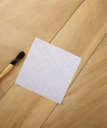 Clear Silicone Furniture Pads 200 Pack No Slip Bumpers For Chair Legs Table Feet on wooden floor with brush nearby.