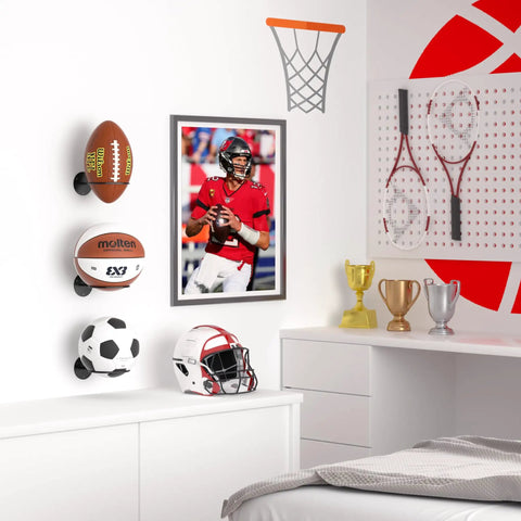 Two Pack Wall Mount Basketball Racks Black Space Saving Ball Holder For Home Gym Or Bedroom Decor Keeps Basketballs Footballs Rugby Balls And Volleyballs Organized Like A Pro In Small Spaces displayed in a sports-themed bedroom with trophies and rackets.