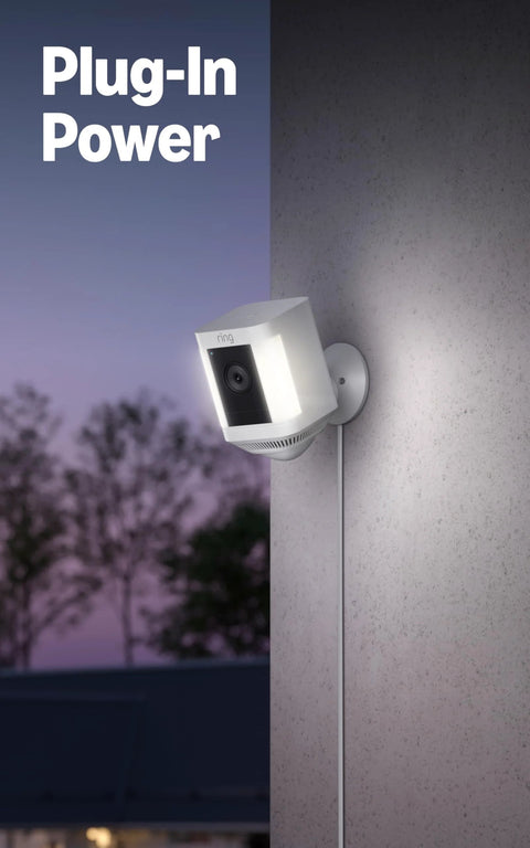 Ring Spotlight Cam Plus security camera, white, mounted on exterior wall with power cord.