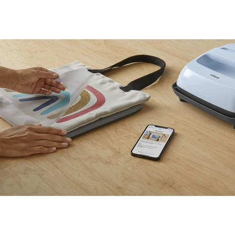 Front view of Cricut EasyPress Mat 12x12, heat-resistant protective mat beside Cricut EasyPress and a tote project