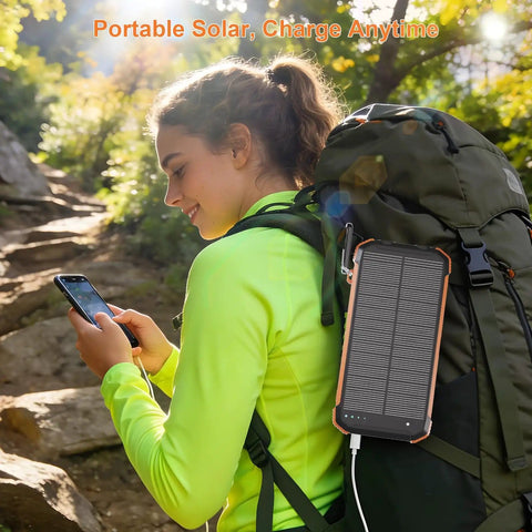 Hiker using Portable Solar Charger And Power Bank With Wireless Fast Charging, 20000mAh Battery Pack attached to backpack.