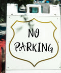 Sidewalk view of a 'No Parking' sign on a white sandwich board, demonstrating potential use for Bulk 360 Piece Self Adhesive Vinyl Letter And Number Sticker Set For Mailboxes Signs Windows Doors Cars Trucks And More 2 Inch Black Waterproof Durable Alphabet And Numerals.