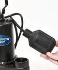 Hand holding 25 Foot Tethered Float Switch For Sump And Sewage Pumps No Mess No Fuss Activation With Mounting Clip And Clamp 120 Volt Power Cord SJOW Water Resistant Piggyback Plug Black, next to a sump pump