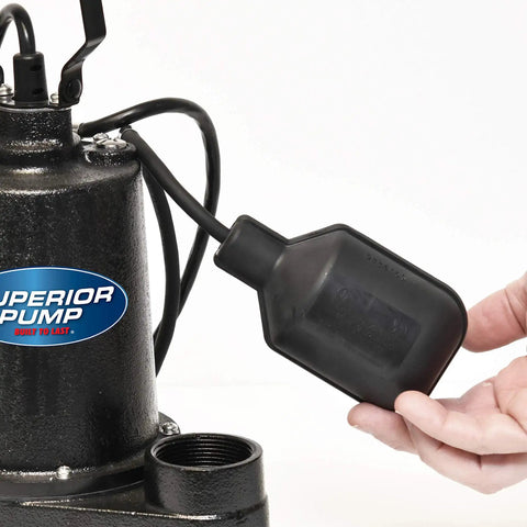 Hand holding 25 Foot Tethered Float Switch For Sump And Sewage Pumps No Mess No Fuss Activation With Mounting Clip And Clamp 120 Volt Power Cord SJOW Water Resistant Piggyback Plug Black, next to a sump pump