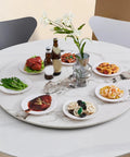 24 Inch Round Marble Lazy Susan Turntable With Tempered Glass Cover featuring dishes and drinks on a dining table
