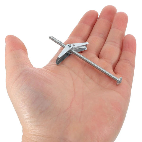 Close-up of 24 Piece Drywall Toggle Anchors And Screws Kit Carbon Steel Spring Loaded Hollow Wall Anchors in a hand for size reference