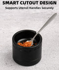 Black spice grinder with smart cutout design, holding a spoon with spices inside, on grey background
