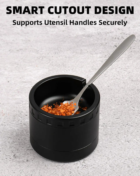 Black spice grinder with smart cutout design, holding a spoon with spices inside, on grey background