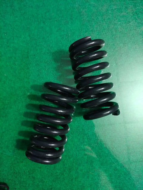 Built Different Heavy Duty Compression Springs Set Of Two High Carbon Steel Industrial Gear resting on green surface.