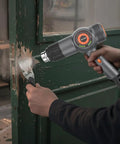 Person using Beast 1800W Heat Gun With Fast Heating, LED Temperature Display to strip paint from a wooden door