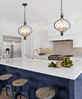 Modern Orb Chandelier With 3 Lights In Black And Gold, Frosted Glass Shades, illuminating a sleek kitchen island.