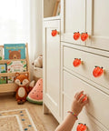 Adorable 3D Peach Cabinet Knobs And Drawer Pulls For A Fresh Playful Home Vibe on white furniture with child's hand reaching.