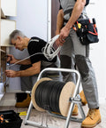 Technicians using Heavy Duty Steel Cable Caddy And Wire Spool Rack Dispenser For Reels Up To 100 Lb in a maintenance setting.