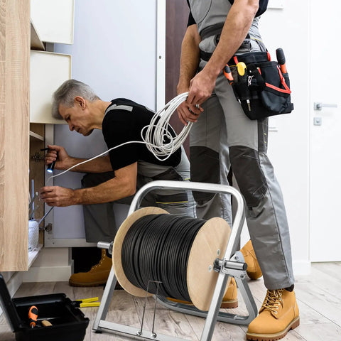 Technicians using Heavy Duty Steel Cable Caddy And Wire Spool Rack Dispenser For Reels Up To 100 Lb in a maintenance setting.