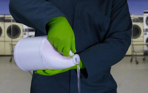 Person wearing Heavy Duty Nitrile Mechanic Gloves 8 Mil With Raised Diamond Texture pouring liquid from a container.