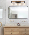 Farmhouse Style Four Light Vanity Light Over Mirror With Rustic Wood Frame And Seeded Glass Shades in bathroom setting