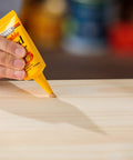 Hand applying Stainable Wood Filler For Cracks And Dings 16 Oz Paintable Latex Formula to wooden surface