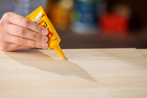 Hand applying Stainable Wood Filler For Cracks And Dings 16 Oz Paintable Latex Formula to wooden surface