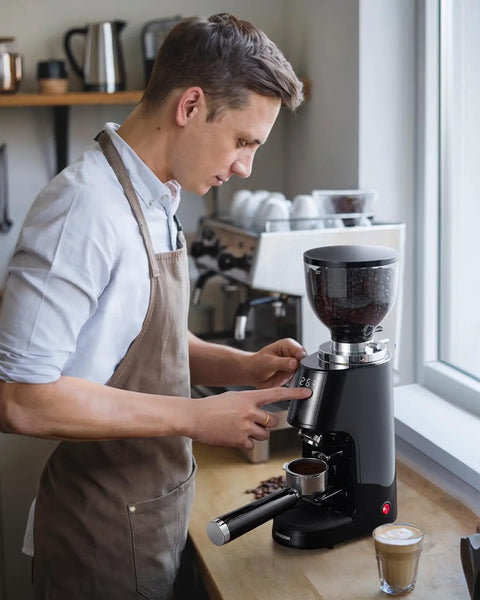 Premium 64Mm Flat Burr Coffee Grinder Featuring 100 Exact Grind Settings And Anti Static Technology For Smooth Daily Brews And Top Shelf Espresso Results In Matte Black in use with a coffee shot.