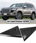 Dope Carbon Fiber Side Mirror Triangle Panel Trim For Land Cruiser J300 LC300 GX GXL VX Sahara ZX GR Sport 2022 To 2026 A Pillar Quarter Window Cover, Scratch Resistant, Ultra Lightweight 3K Weave Exterior Accent shown next to a Land Cruiser LC300
