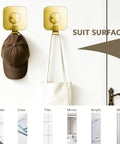 Heavy Duty Adhesive Wall Hooks In A Dope Four Pack, Stainless Steel Stick On Hangers With Badass Grip For Bathrooms And Kitchens, Waterproof And Super Fast To Put Up On Any Wall Or Door Without Drilling, Classic Gold Finish holding a cap and bag.