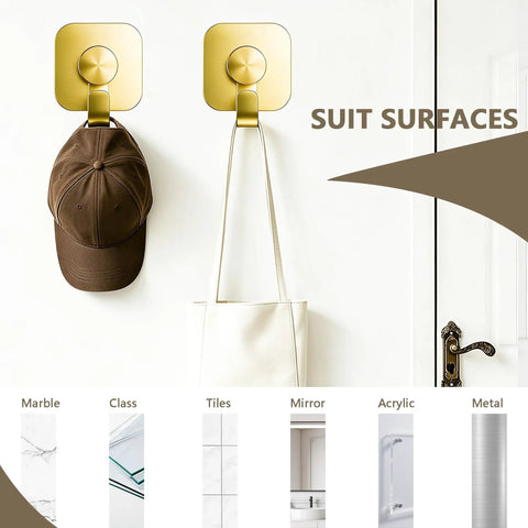 Heavy Duty Adhesive Wall Hooks In A Dope Four Pack, Stainless Steel Stick On Hangers With Badass Grip For Bathrooms And Kitchens, Waterproof And Super Fast To Put Up On Any Wall Or Door Without Drilling, Classic Gold Finish holding a cap and bag.
