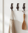 Kickass Cast Iron Dog Tail Hooks, Straight Up 4 Pack Wall Mount Leash Holders With Screws and Anchors, rustic hooks holding a bag and wooden spatula.