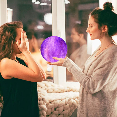 Two women with Moon Lamp Galaxy Night Light 3D Printed LED Moon Light With Stand 16 Color Options Remote And Touch Control USB Rechargeable.