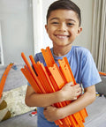 Child smiling holding orange track pieces from BHT77 Diecast Car and Track Pack in living room