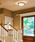 Gold 2-Light Flush Mount Ceiling Light With Milk Glass Shade, Brass Finish, installed in a modern foyer.